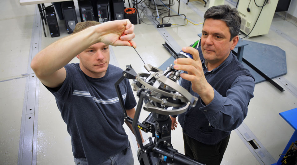 Professor Stanisic working on a mechanical device with a Notre Dame engineering student.